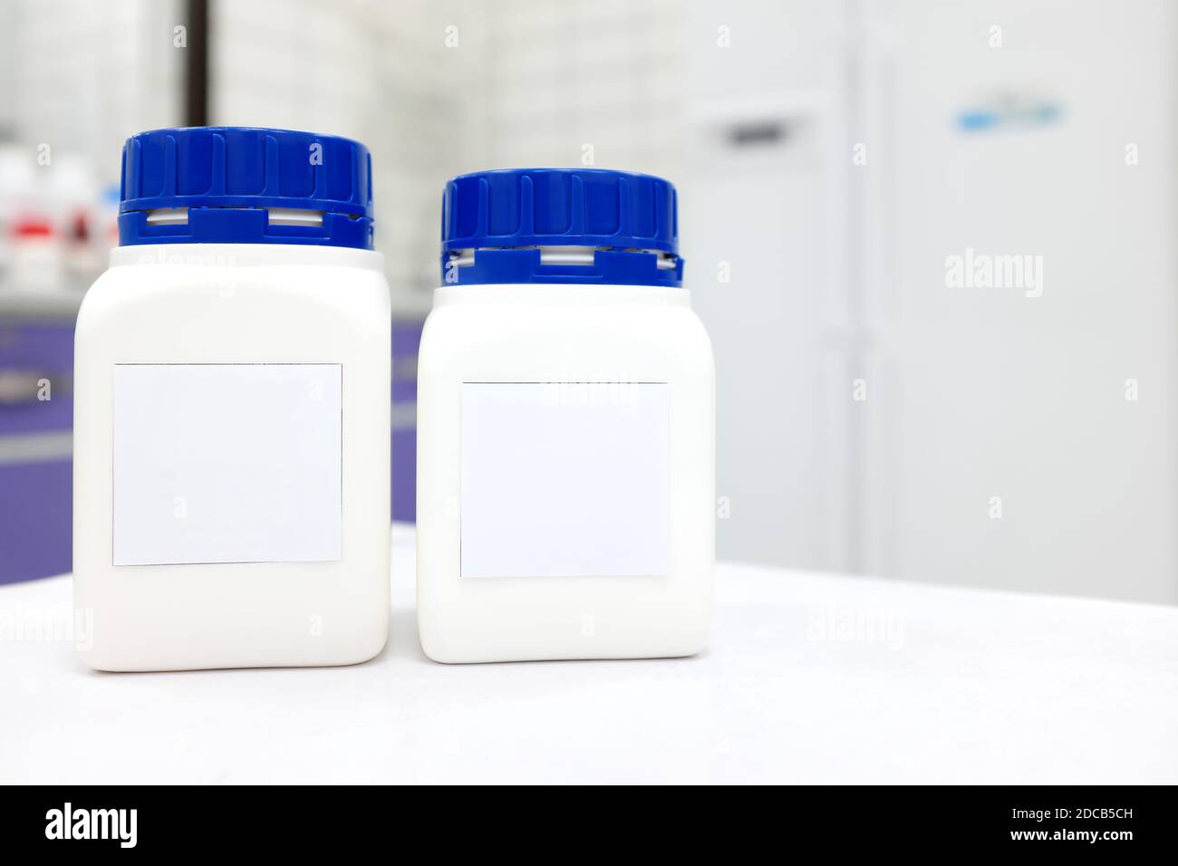 Two unlabeled plastic chemical bottle container with cap in a white chemistry laboratory with copy space. Stock Photo