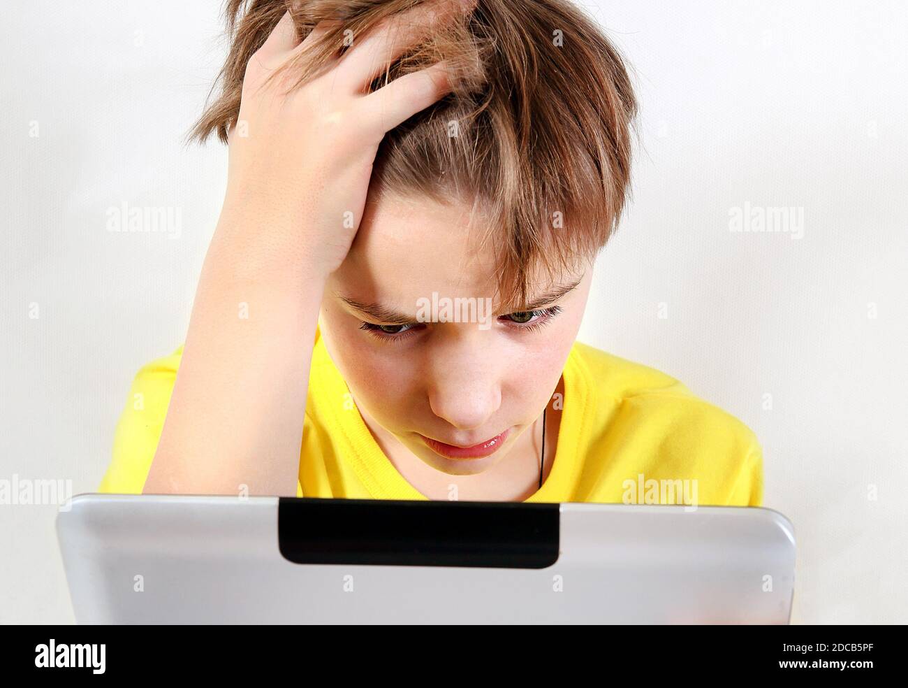 Sad Kid with Tablet Computer on the White Wall Background Stock Photo