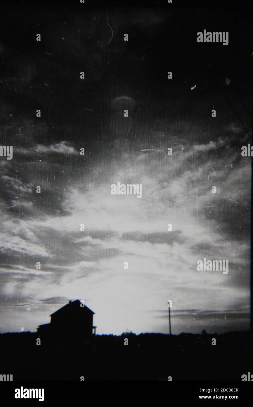 Fine 1970s vintage black and white photography of an old abandoned home in profile against the golden hour sunset. Stock Photo