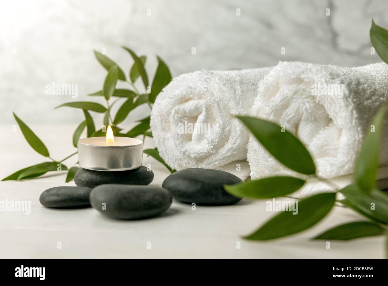 spa stones with white towels, burning candle and green plant Stock Photo