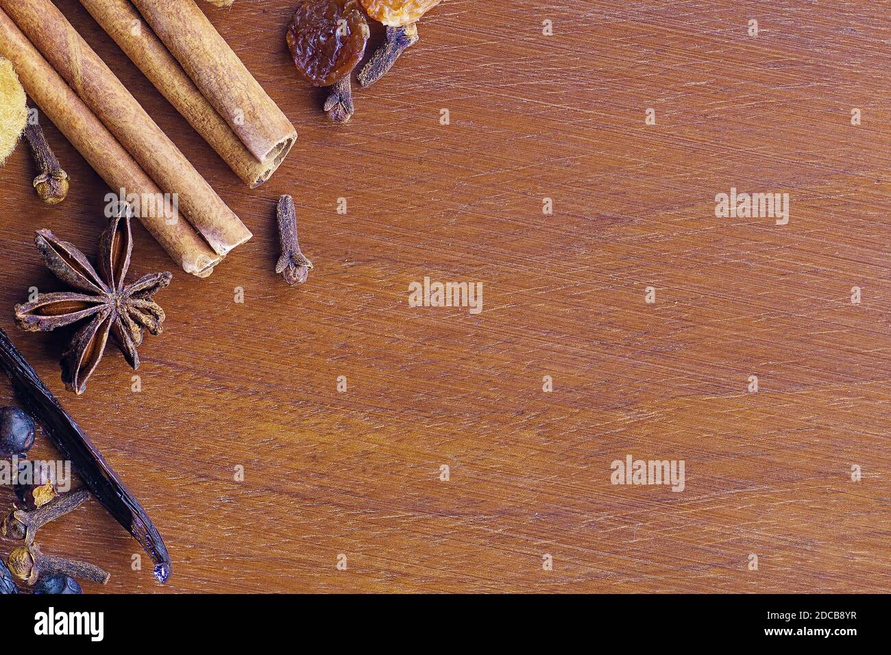 Close-up of cinnamon sticks, star anise, bourbon vanilla beans, cloves, juniper berries on a wooden walnut cutting board. Food, spices and Christmas c Stock Photo