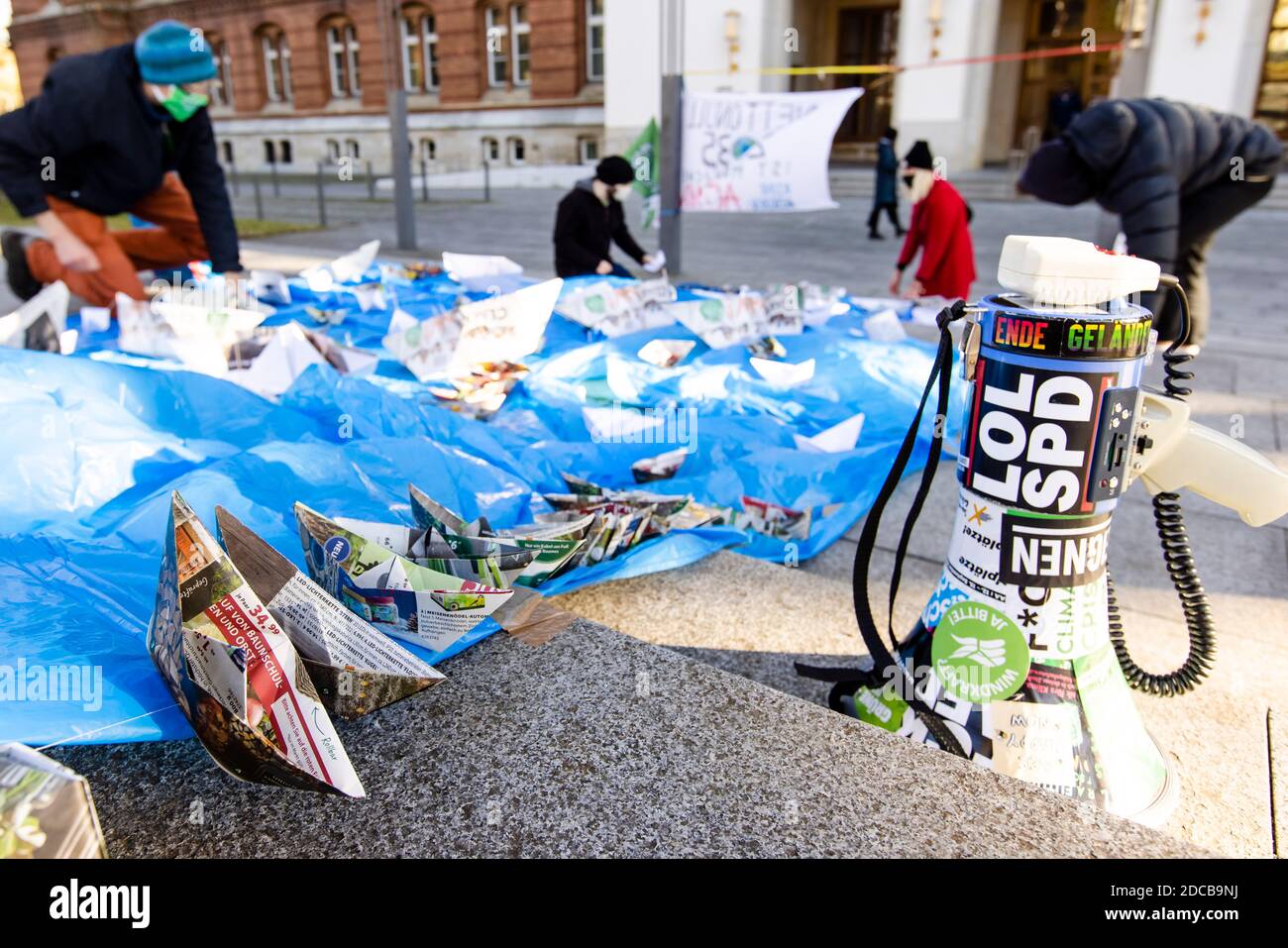 Kiel, Germany. 20th Nov, 2020. Activists of the climate movement Fridays  for Future put paper boats on a blue plastic foil in front of the Kiel  state parliament. With this action the