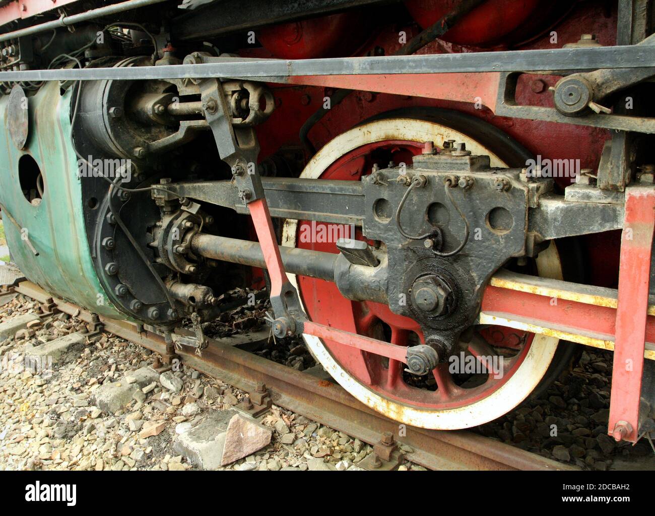 Antique locomotive driving wheels detail. Steam piston, painted wheel and connecting rods. Stock Photo