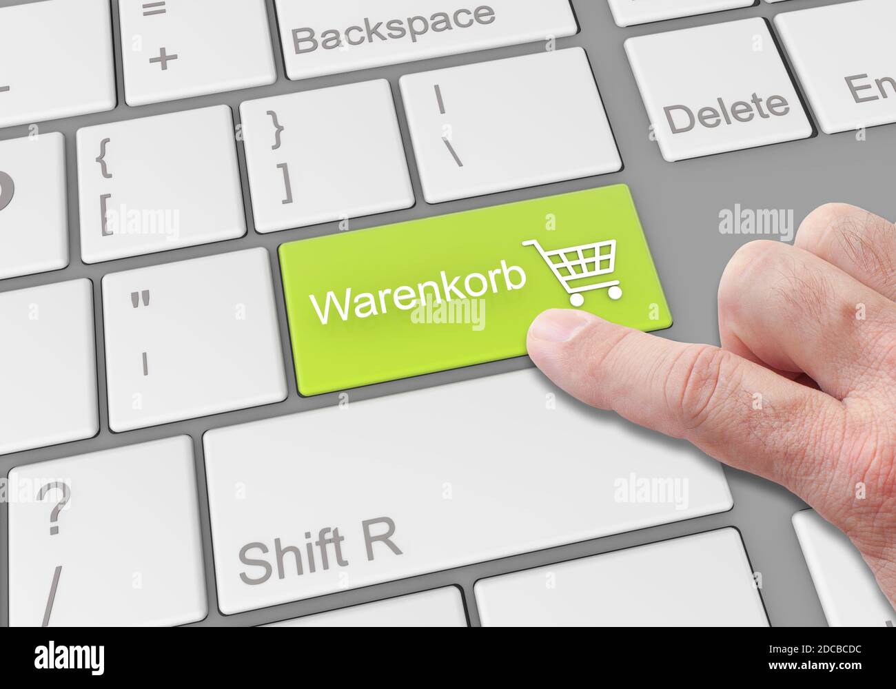 A person clicking a special 'warenkorb' button on a laptop keyboard Stock Photo
