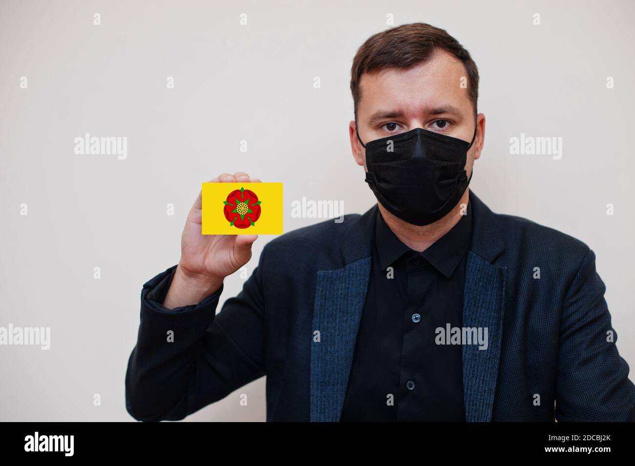 Man wear black formal and protect face mask, hold Lancashire flag card isolated on white background. United Kingdom counties of England coronavirus Co Stock Photo