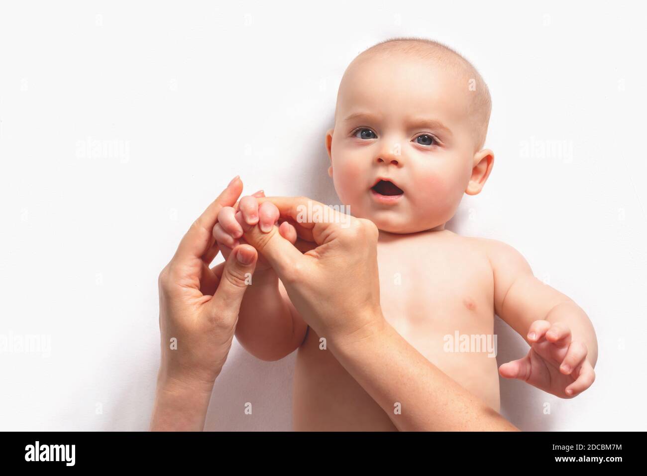 Mum is making hand massage caucasian child up to one year. Gymnastics for small kids. Close up. Top view. Stock Photo