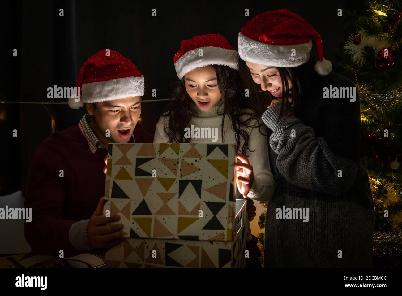 Happy family portrait, father mother and daughter, celebrate Christmas and New Year together, opening gift box with magically surprise Stock Photo