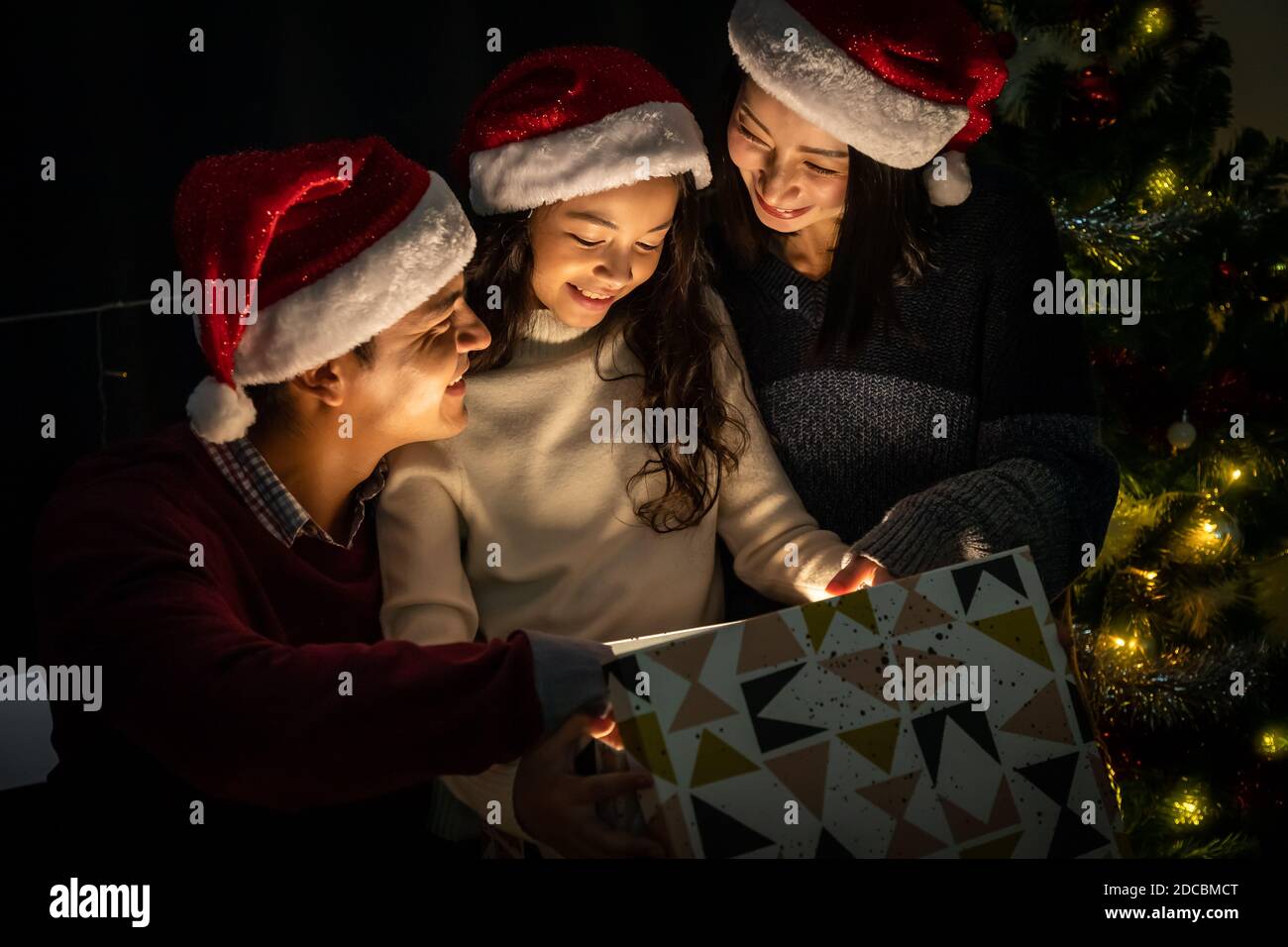 Happy family portrait, father mother and daughter, celebrate Christmas and New Year together, opening gift box with magically surprise Stock Photo
