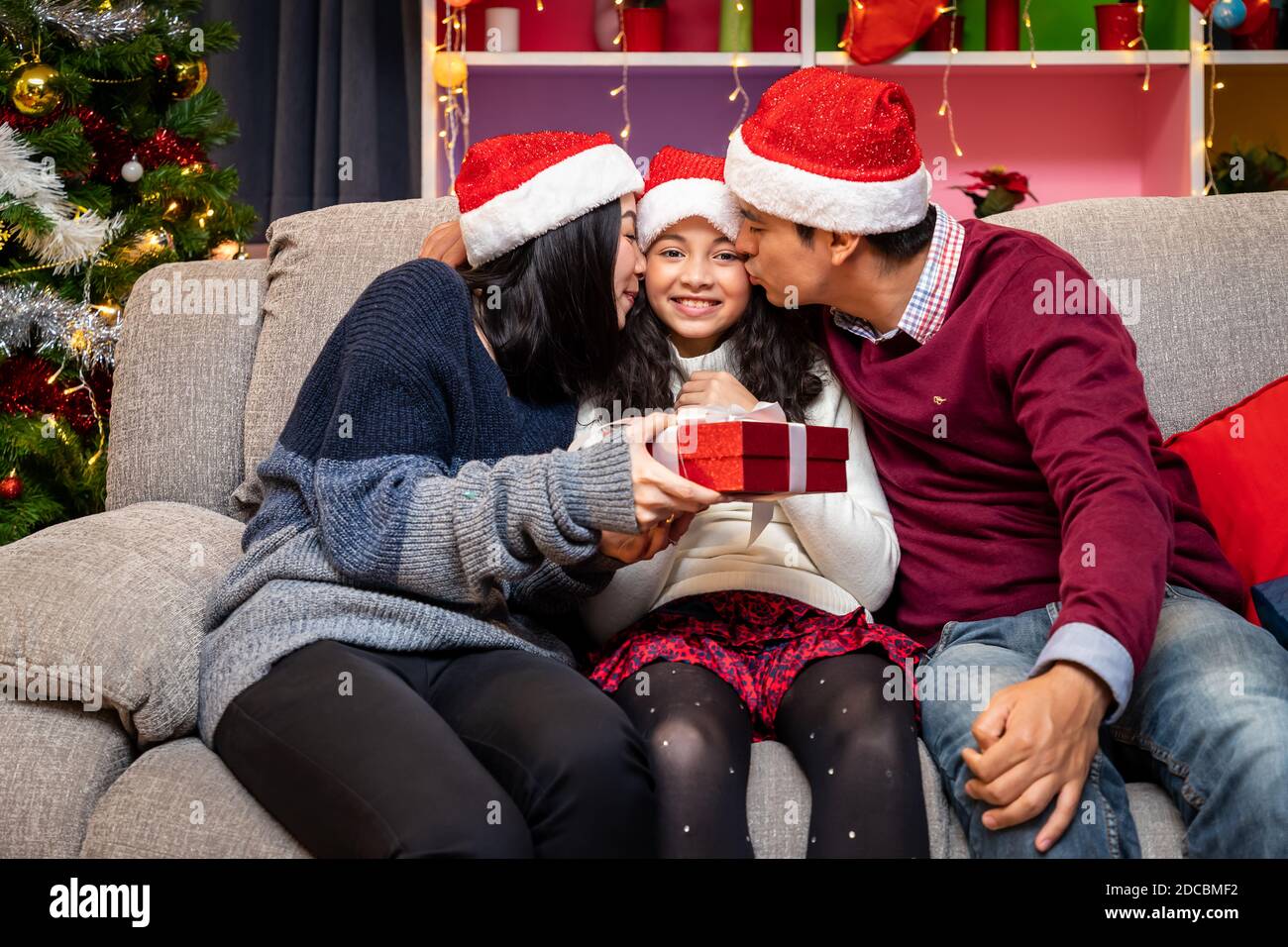 Portrait of happy family, father mother and daughter, celebrate Christmas in living room, sitting on sofa, holiday season Stock Photo