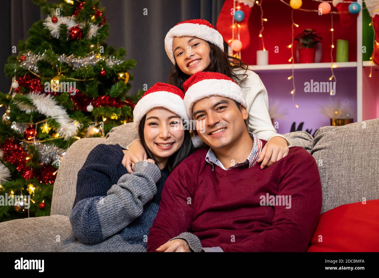 Portrait of happy family, father mother and daughter, celebrate Christmas in living room, holiday season Stock Photo