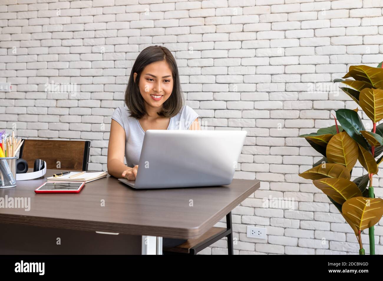 Portrait of Asian woman freelancer working at home, sitting at desk dining table in living room Stock Photo