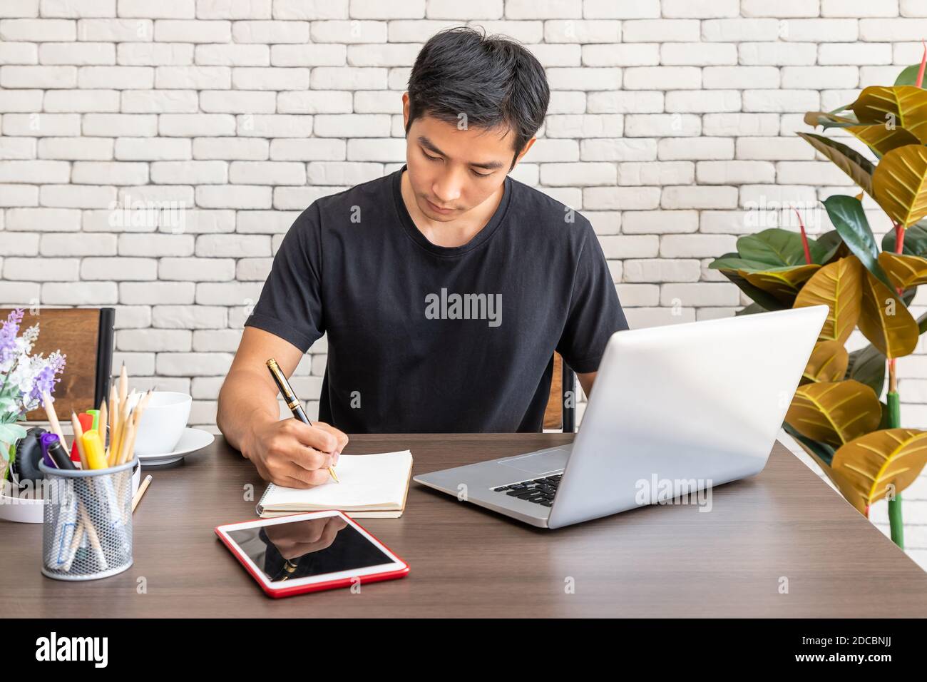Portrait of Asian man freelancer working at home, sitting at desk dining table in living room Stock Photo