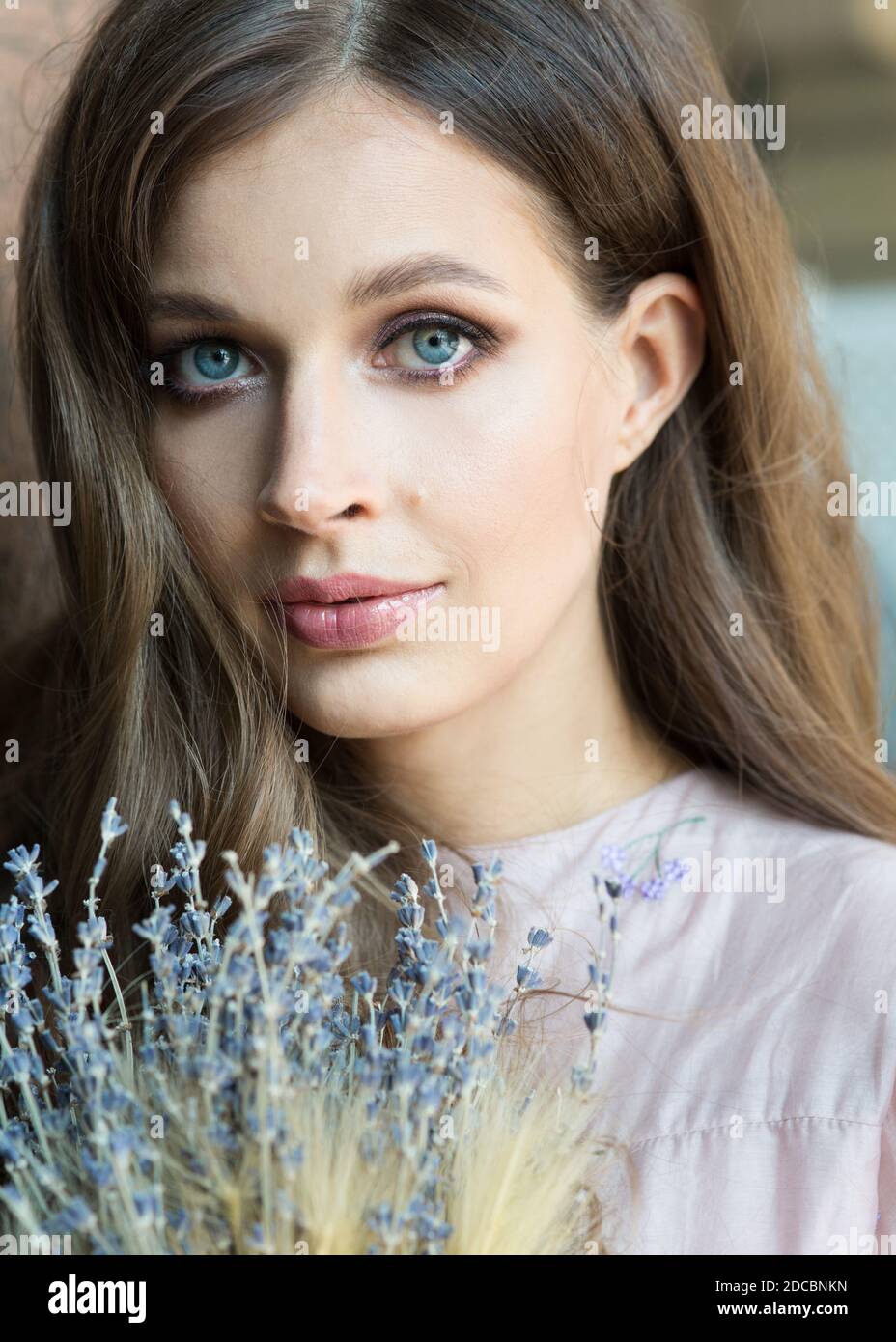 Close up portrait of a beautiful girl with a lavender in a fashionable pink dress stands and smiles on a background with artistic spots Stock Photo