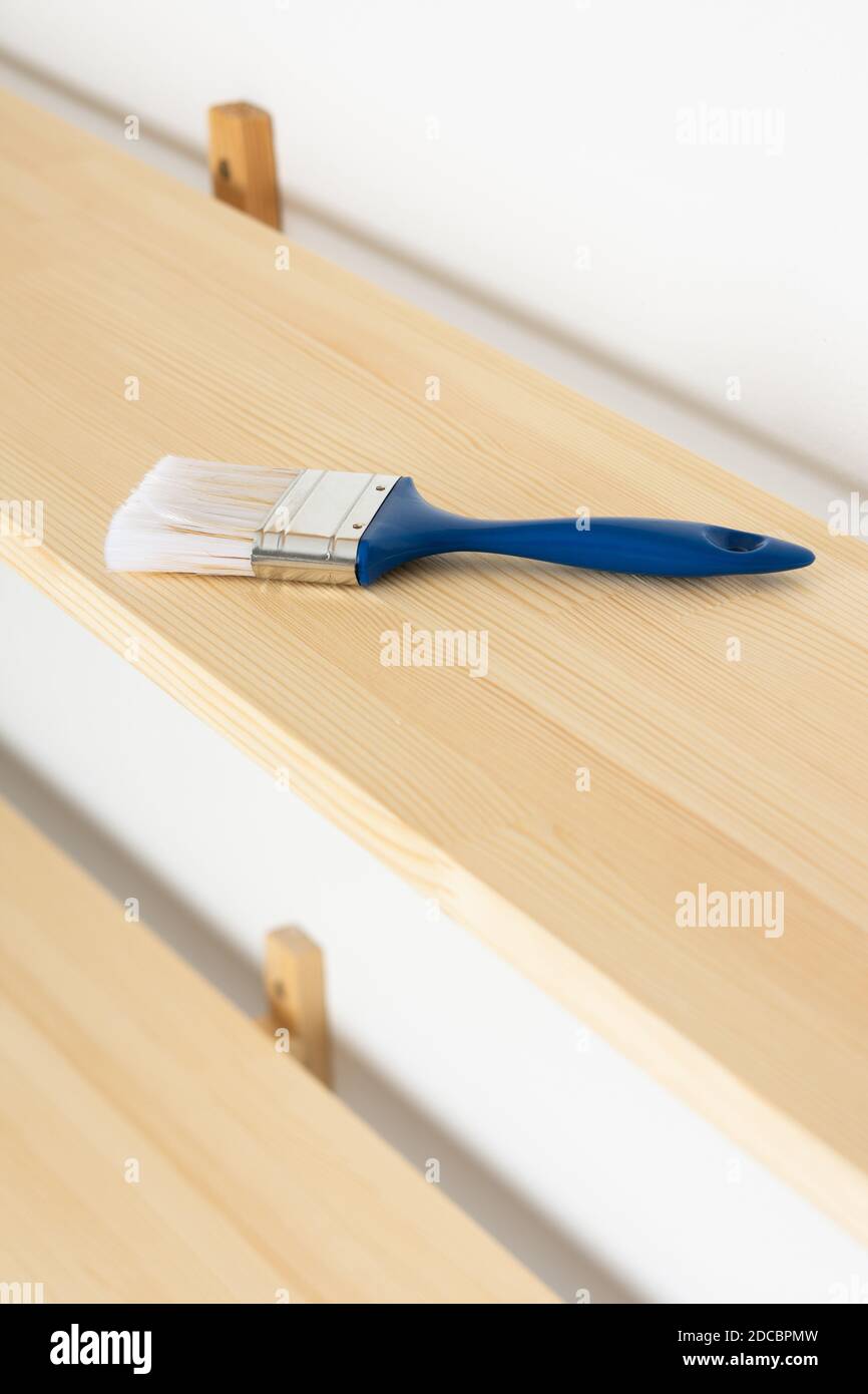 Paint brush on a wooden shelf, the process of varnishing or painting