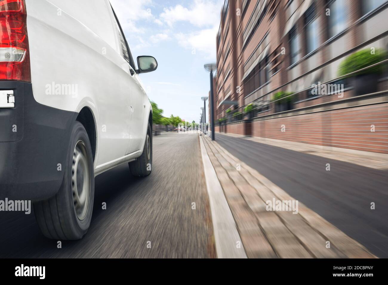 White delivery van driving on a street in the city Stock Photo - Alamy