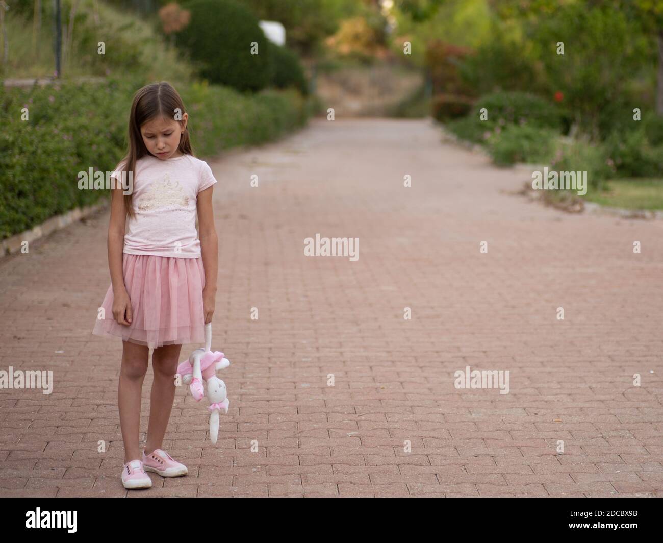 Sad girl hugging teddy bear sadness alone in green garden park. Lonely
