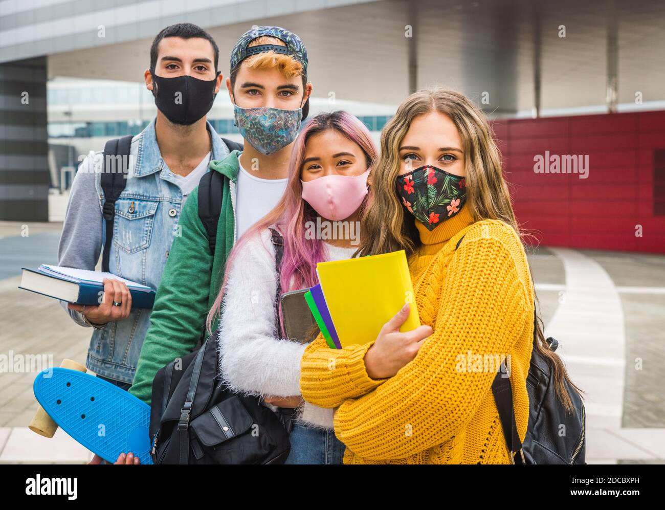 Happy young people meeting outdoors and wearing face masks during covid ...