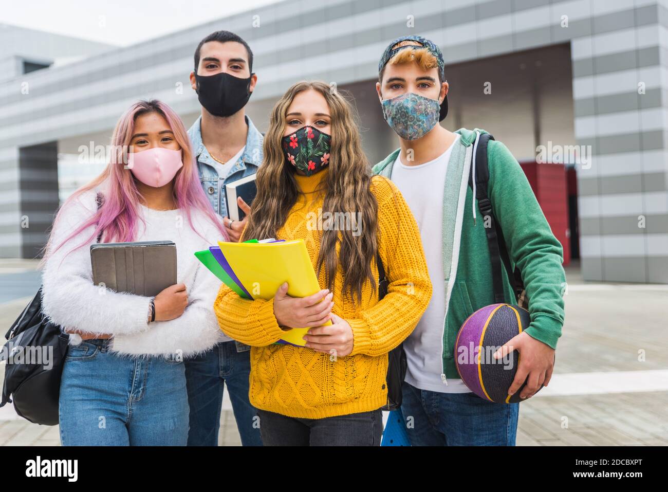 Happy young people meeting outdoors and wearing face masks during covid ...