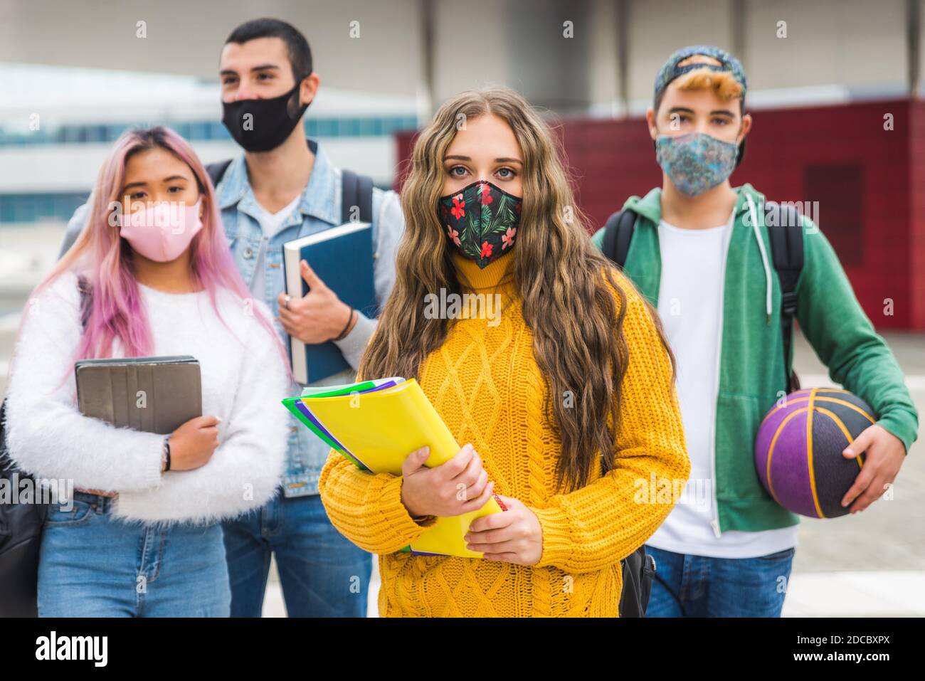 Happy young people meeting outdoors and wearing face masks during covid ...