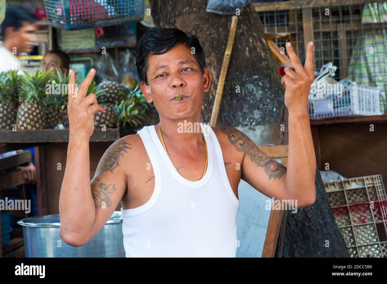 Daily life in Myanmar - male stall holder posing for photo showing peace sign at Yangon, Myanmar (Burma), Asia in February Stock Photo