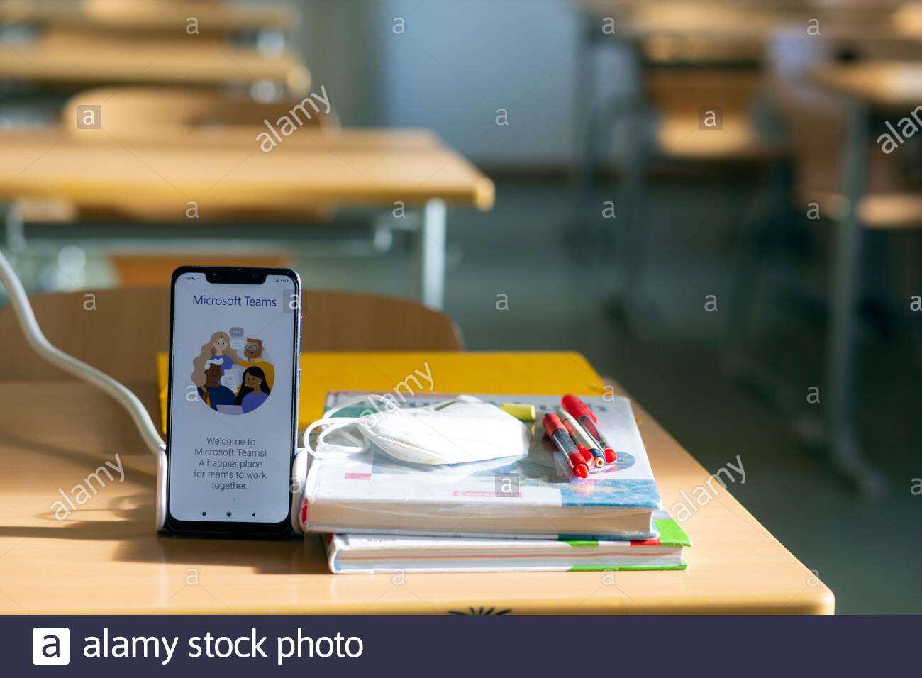 A teacher's mobile phone with Microsoft Teams on it beside books, mask and pens before an online lesson. Rising Corona infections mean that many teachers and children are self-isolating and distance learning is being used again.. Stock Photo