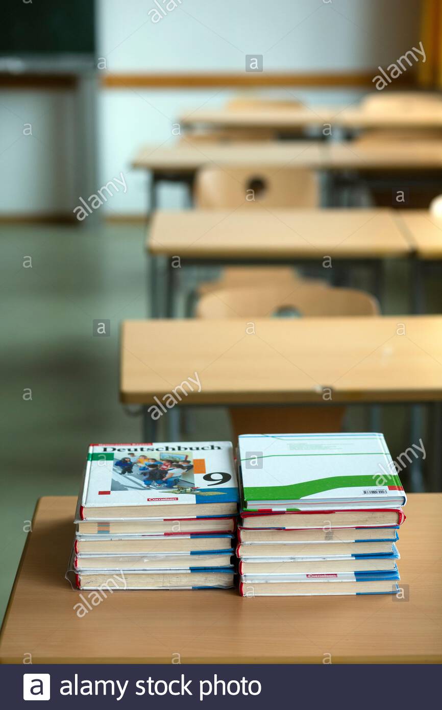 Unused textbooks on a school desk in an empty classroom in a Bavarian school this afternoon. Increasing numbers of students and teachers are having to self-isolate due to Corona virus infections. Stock Photo