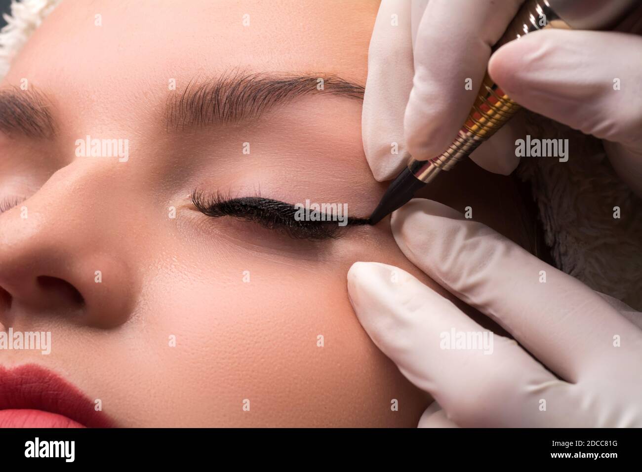 Permanent eye makeup close up shot. Cosmetologist applying tattooing of eyes. Makeup eyeliner procedure. Stock Photo