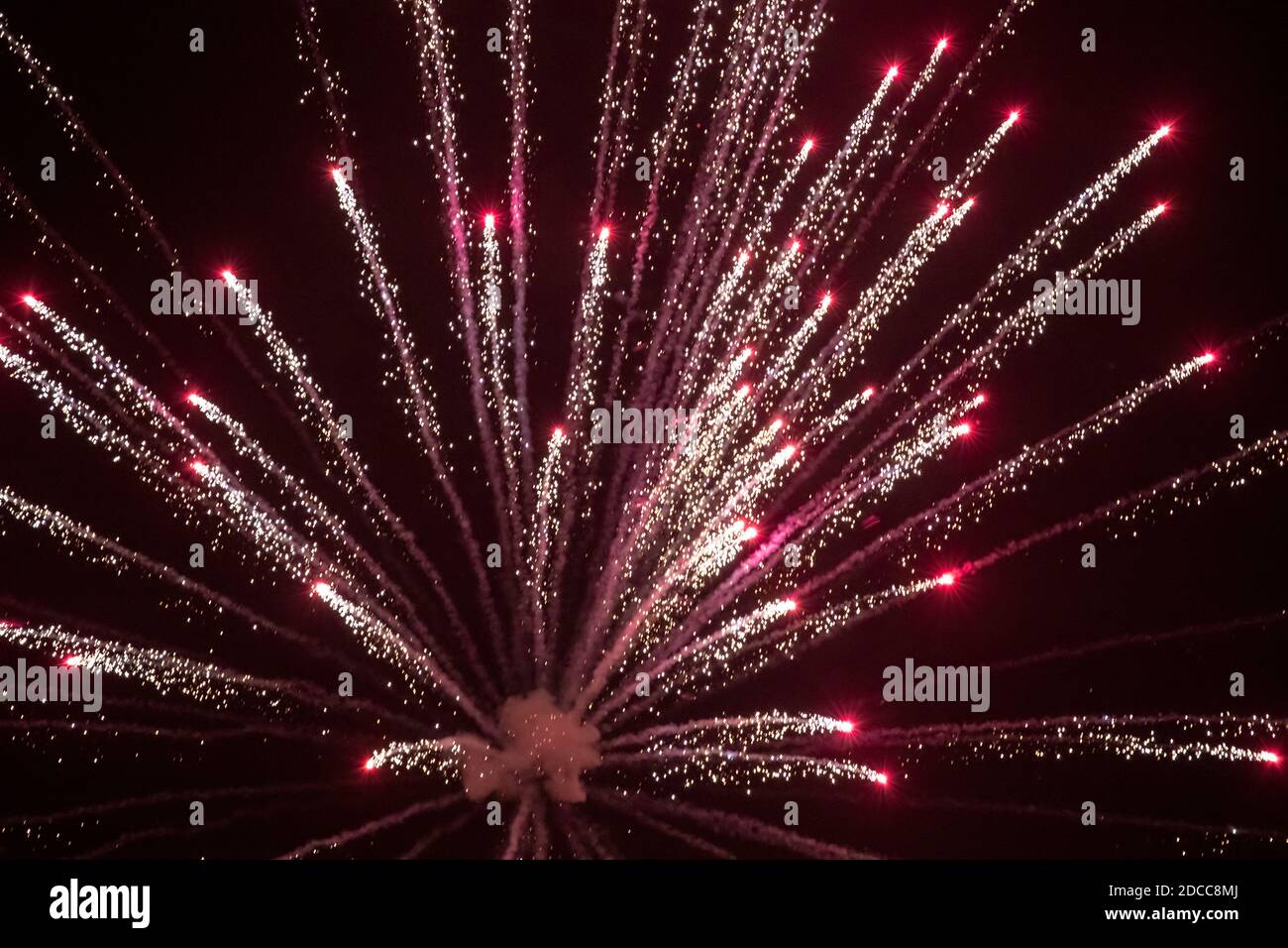 Burst of red and silver light as a pyrotechnic display firework explodes against the dark night sky in West Yorkshire U.K. Stock Photo
