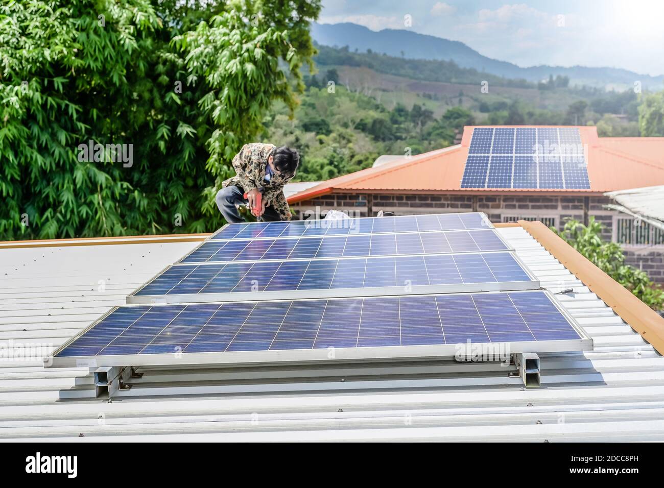 man installing solar panels on a roof house for alternative energy photovoltaic safe energy. power from nature sun power solar cell generator. Stock Photo