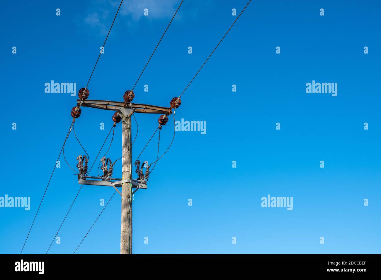 Wooden telegraph pole with wires and insulators with a clear blue sky background Stock Photo