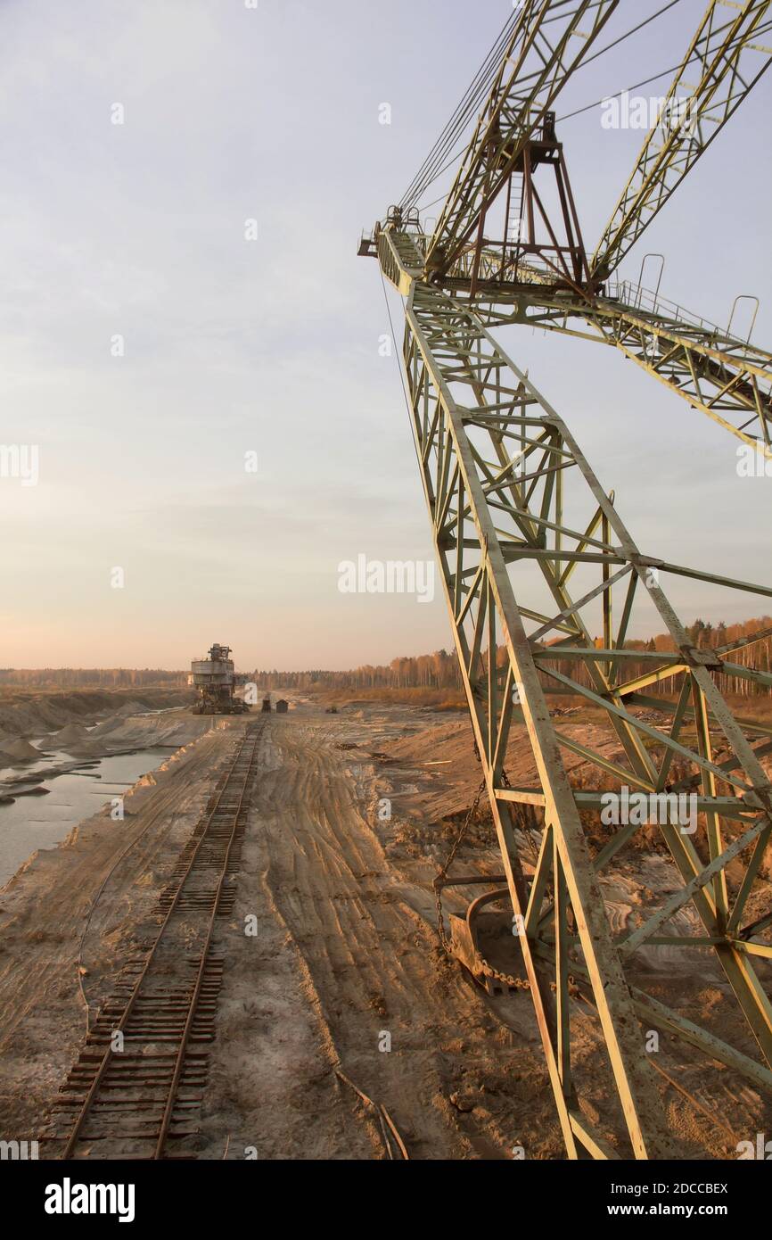 A dragline excavator and a stacker in a sand quarry. Old abandoned railway track. Phosphorite Mine Stock Photo