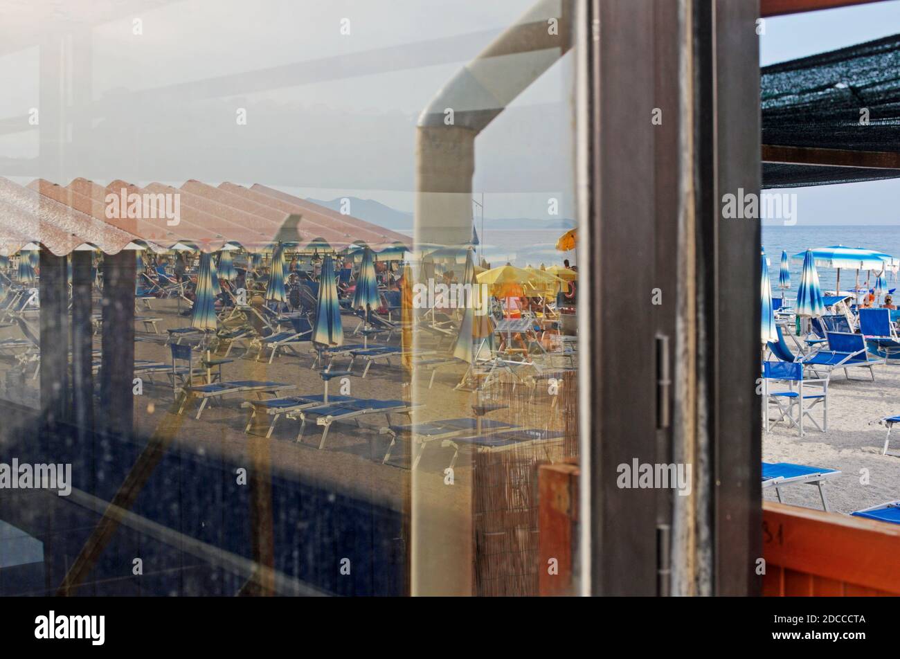 view of a beach through glass door, Finale Ligure, Italy Stock Photo