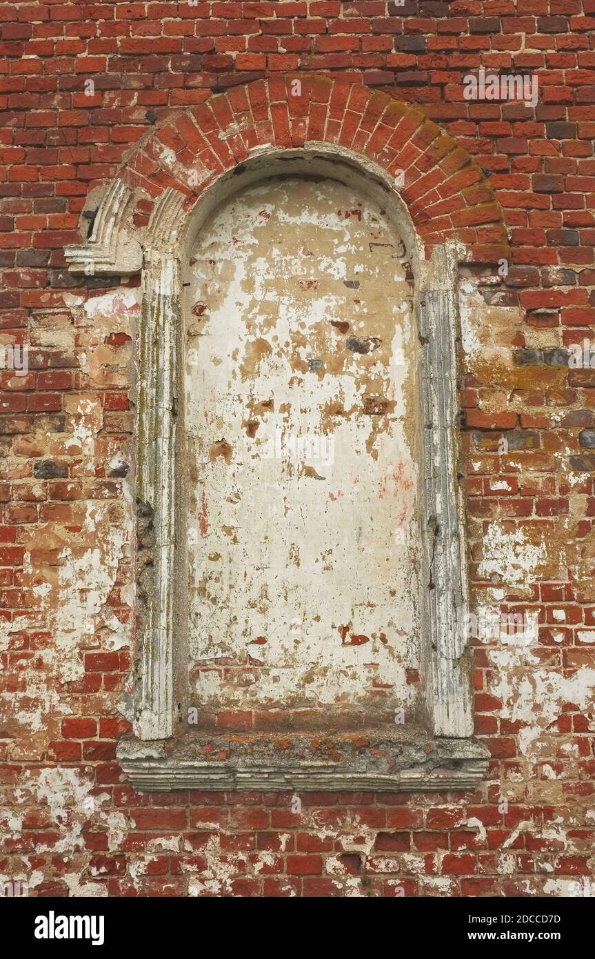Old arched window on a red brick wall of christian church Stock Photo