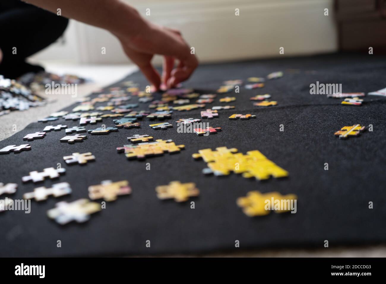 A teenager doing a jigsaw puzzle at home on a black cloth puzzle mat on