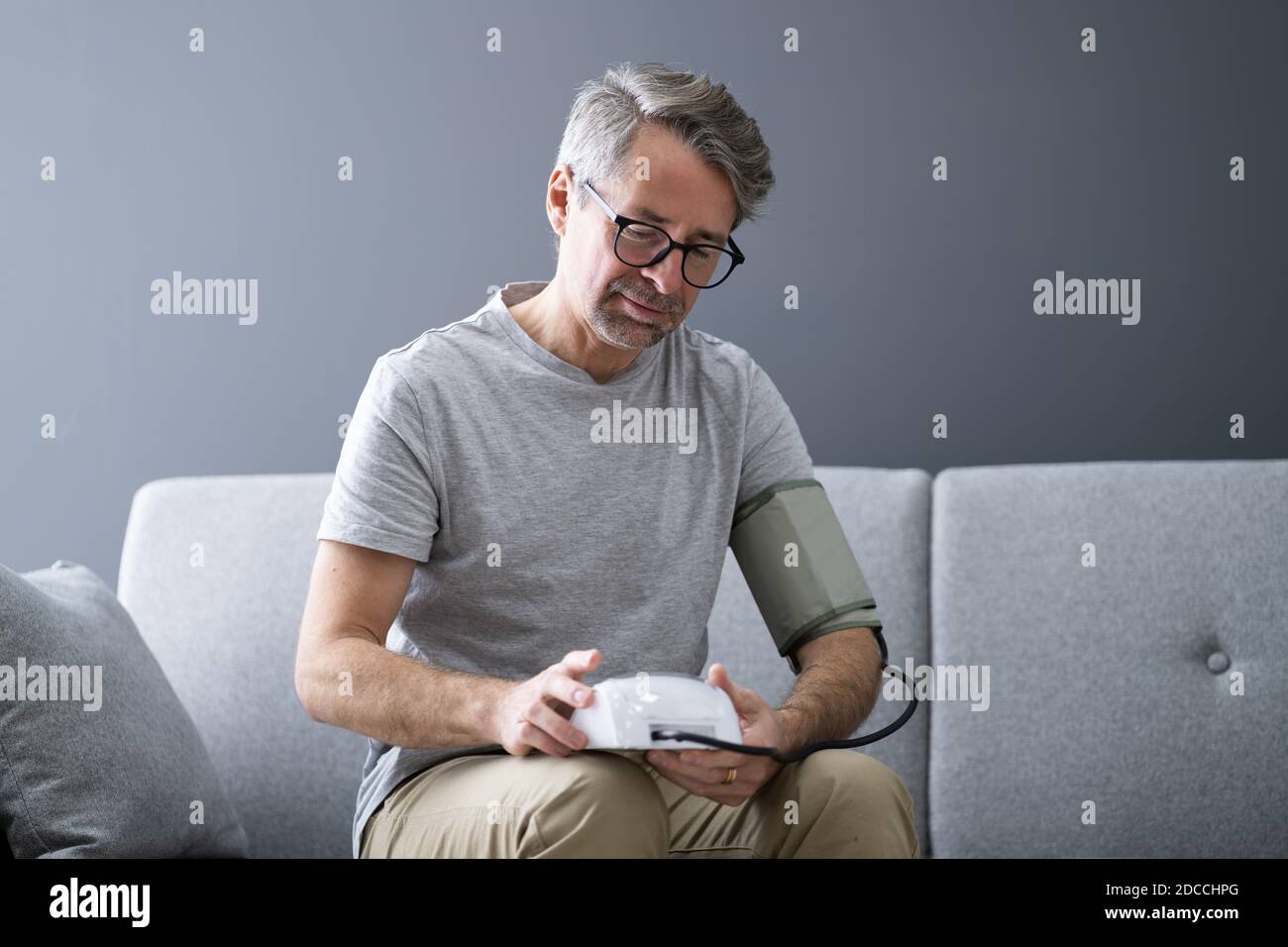 Elder Man Checking Blood Pressure At Home Stock Photo