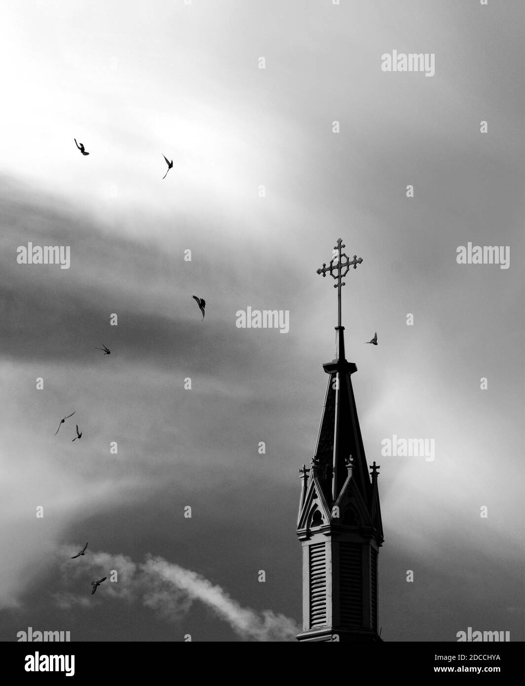 A flock of pigeons circle the Christian cross atop the historic Loretto Chapel in Santa Fe, New Mexico. Stock Photo