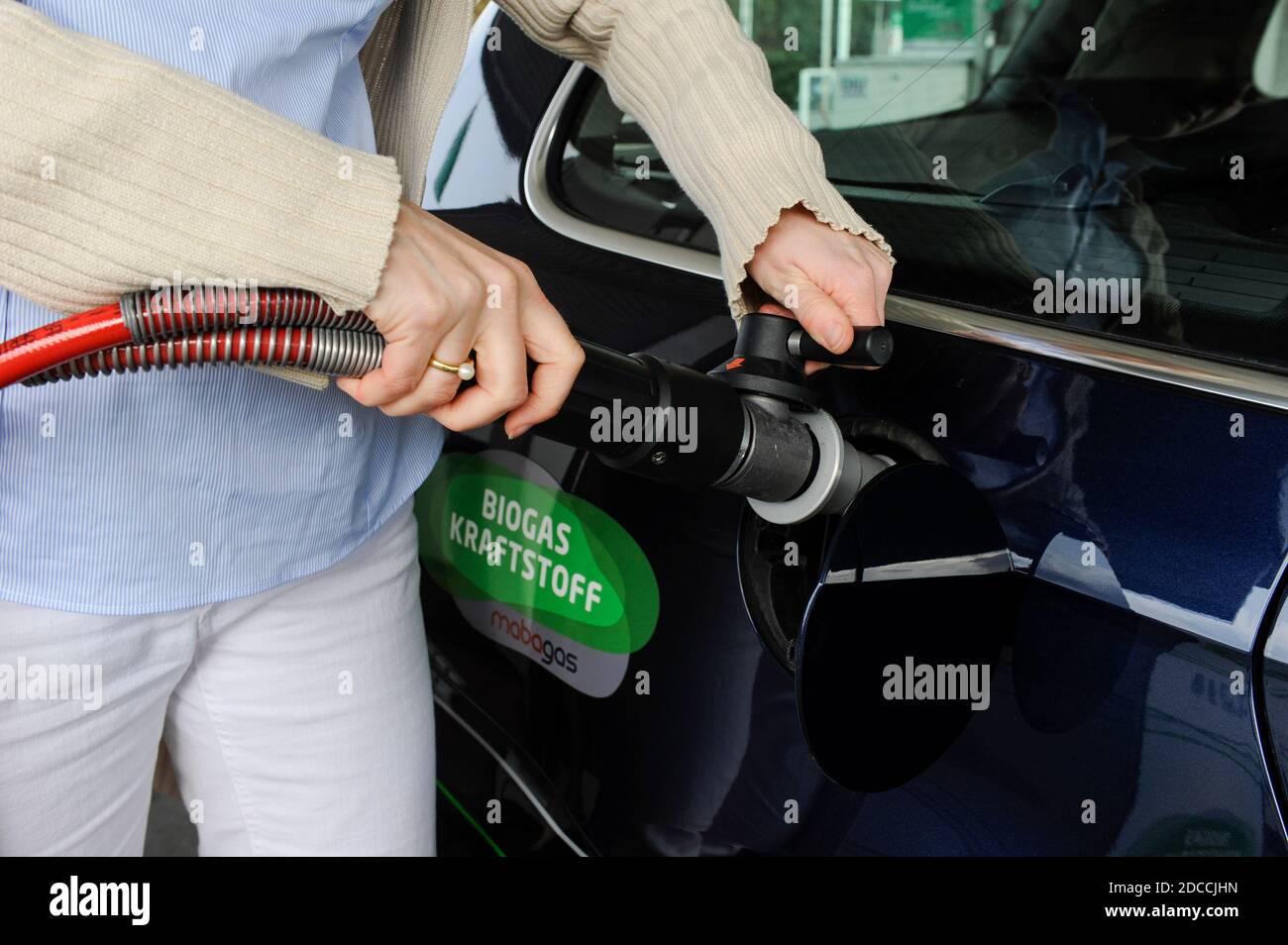 GERMANY Hamburg, fuel station sells Bio CNG, which is biomethan from Biogas fermented from waste or garbage, woman with fuel pistol / DEUTSCHLAND Hamburg, Verkauf von Bio-CNG, Biomethan aus 100% Biogas aus fermentierten  Abfallstoffen gewonnen, durch Firma Mabagas an einer Oil Tankstelle in Schenefeld Stock Photo