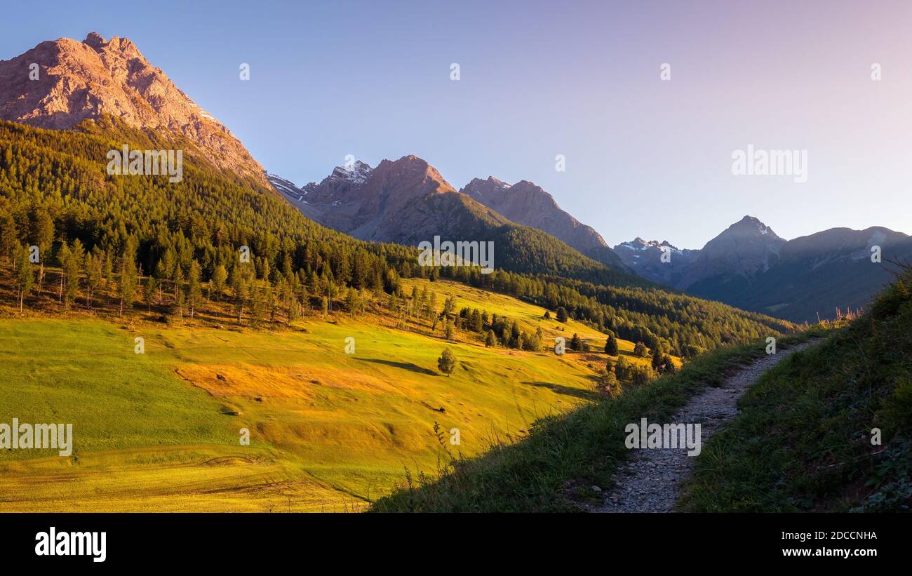 The sun is setting at the mountains surrounding Tarasp, a village in Graubünden, Switzerland. It is situated within the Lower Engadin valley along the Stock Photo