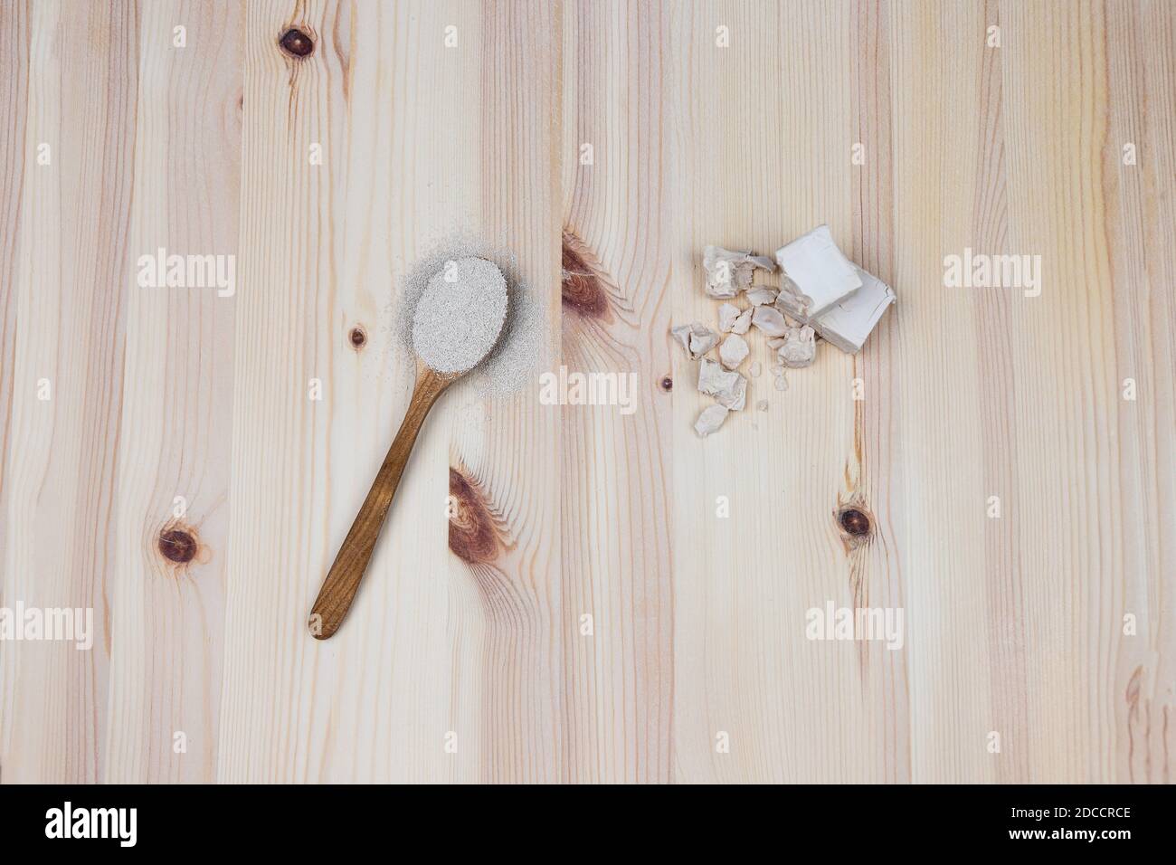 Two different types of yeast on wooden background. Dry yeast in a wooden spoon and fresh bakers yeast in cubes and broken pieces. Baking and making br Stock Photo