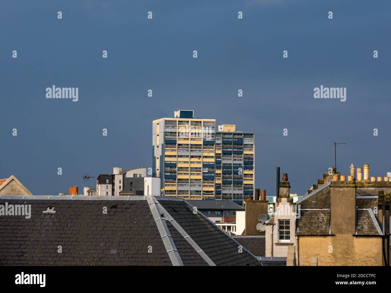 Council tower block of flats towering over rooftops with dark sky, Leith, Edinburgh, Scotland, UK Stock Photo
