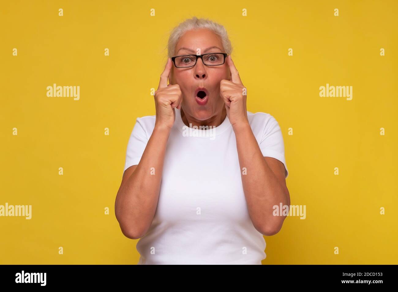 Shocked senior woman , keeping hands up looking with great surprisment and amazement into camera, receiving interesting news from her relatives or fri Stock Photo