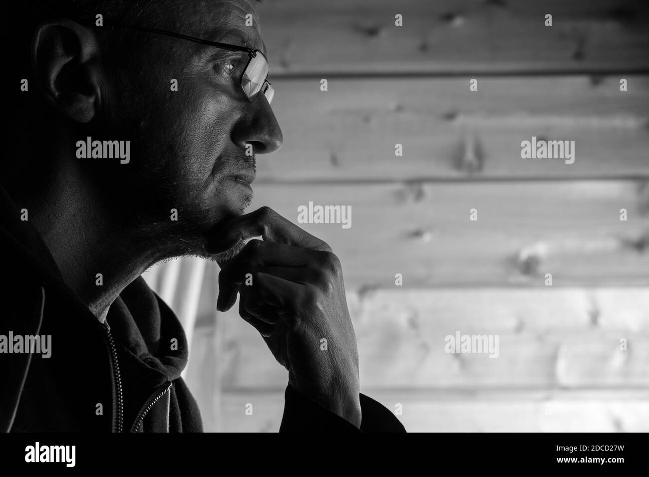 Black and white portrait of mid adult man wearing eyeglasses looking at computer display and thinking. Stock Photo