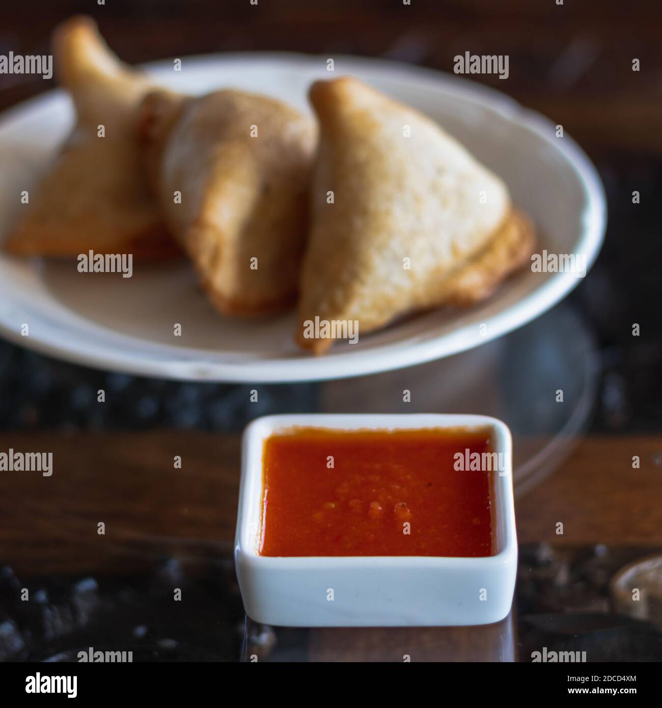 Samosas on a white plate with dipping spicy red sauce Stock Photo Alamy