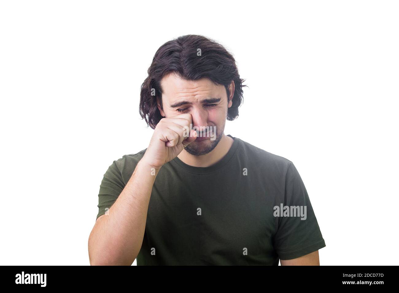 Portrait of desperate young man crying and wiping the tears with his hand isolated on white background. Dissatisfied and disappointed guy sobbing and Stock Photo