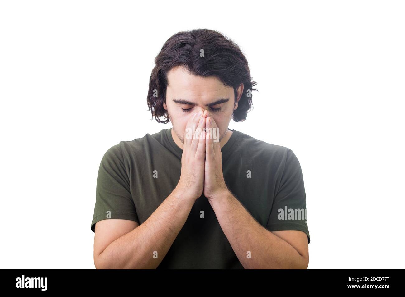 Portrait of depressed young man keeps hands together as prayer, eyes