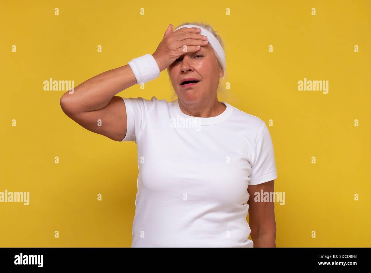 Senior caucasian woman tired rubbing head being exhausted after training. stress and frustration concept. Stock Photo