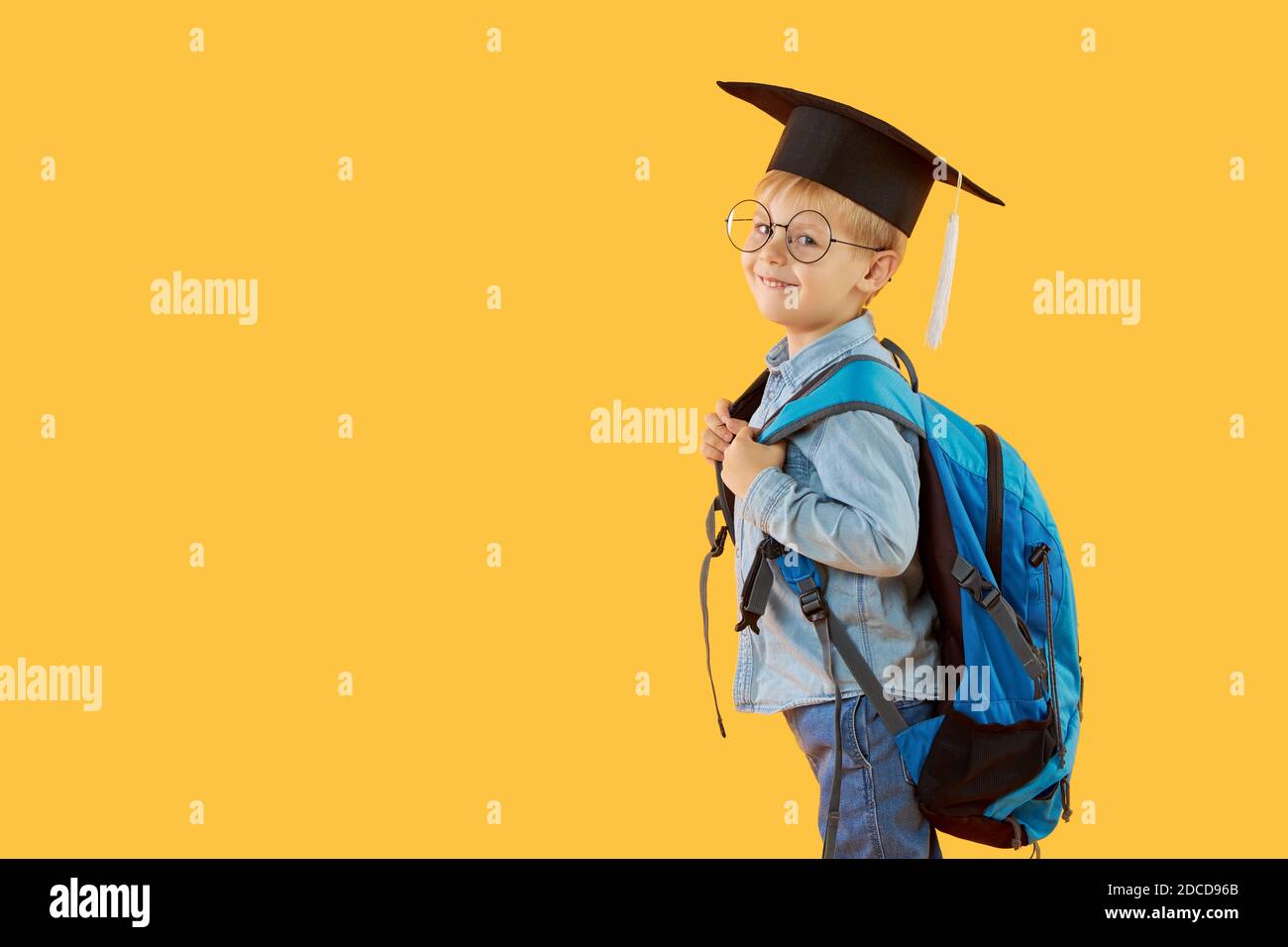 Child boy primary school student in a graduate cap glasses and with a backpack on a yellow background. Knowledge day and back to school. Copy space Stock Photo Alamy