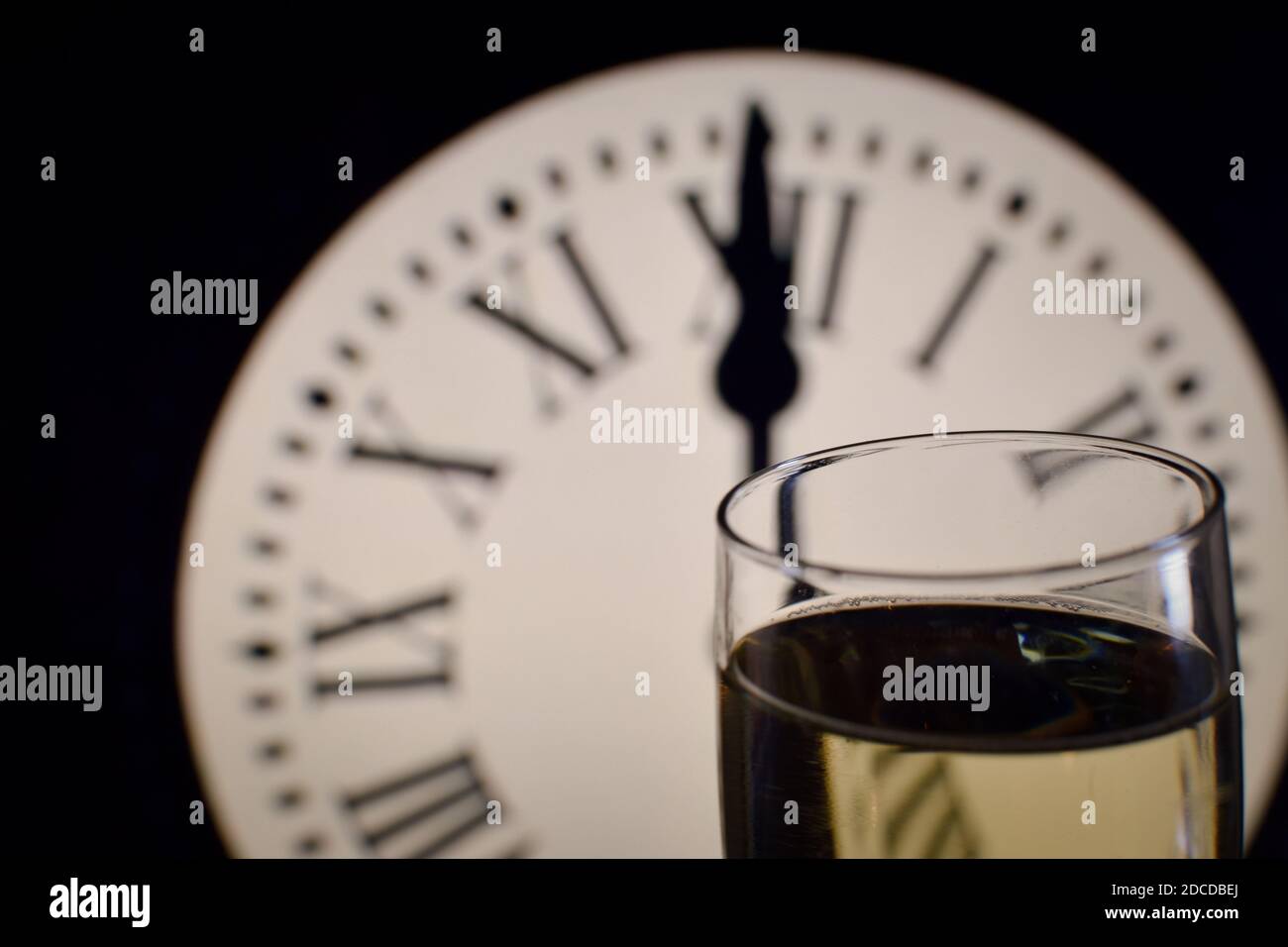 CELEBRATION OF THE NEW YEAR, glasses raising with champagne with the clock unfocussed Stock Photo