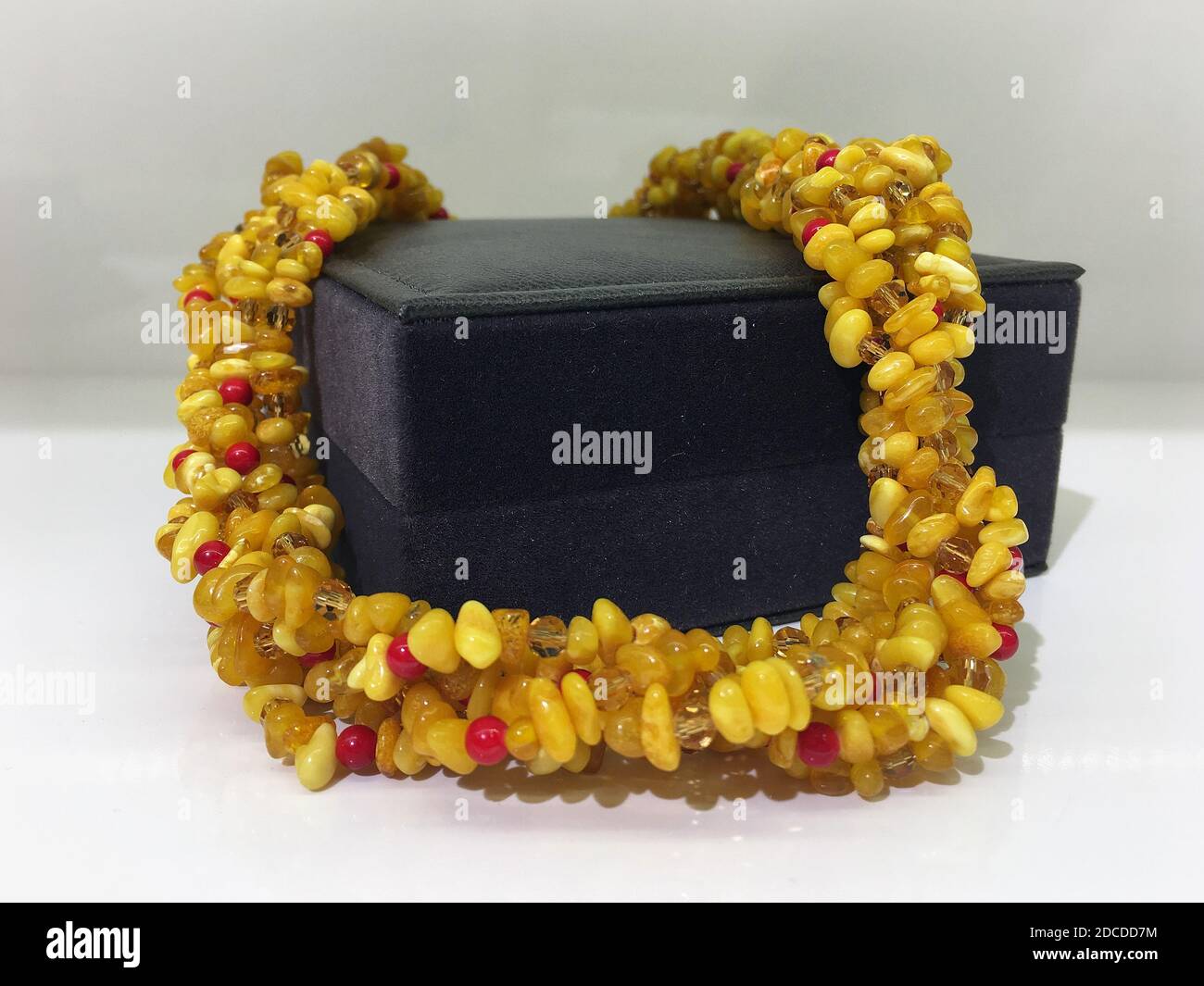 Handmade beaded amber beads lie on a dark gift jewelry box. Stock Photo