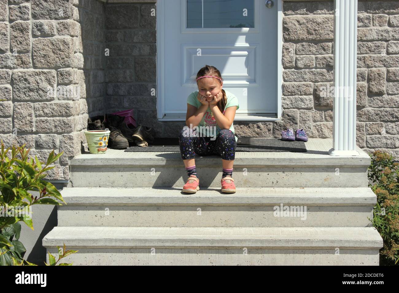Young girl sitting on the front porch of her house mad and pouting ...